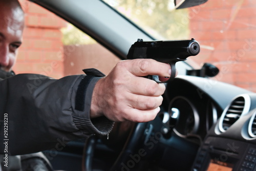 Killer in a car with a gun. The assassin shoots at point blank range.
