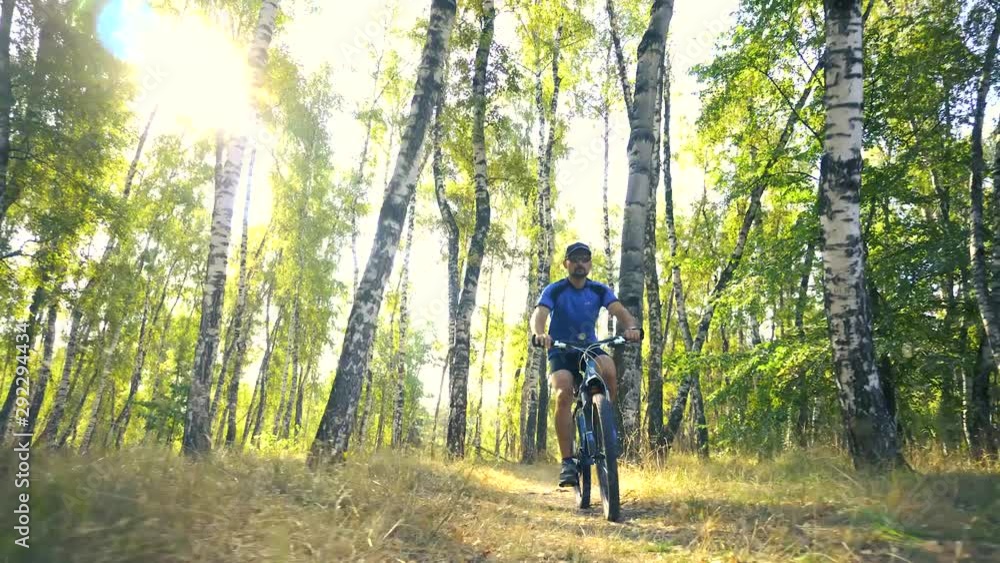 Young man biking on a forest road in a sammer day. active recreation, sport, healthy lifestyle. slow motion Young man biking on a forest road in a sammer day. active recreation, sport, healthy lifestyle. slow motion