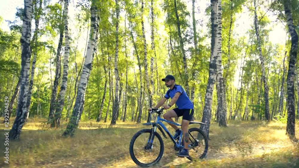 Young man biking on a forest road in a sammer day. active recreation, sport, healthy lifestyle. slow motion Young man biking on a forest road in a sammer day. active recreation, sport, healthy lifestyle. slow motion