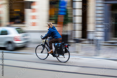 Ghent, Belgium; 10/31/2018: Panning effect photography of a woman riding on a bike through a street in the city