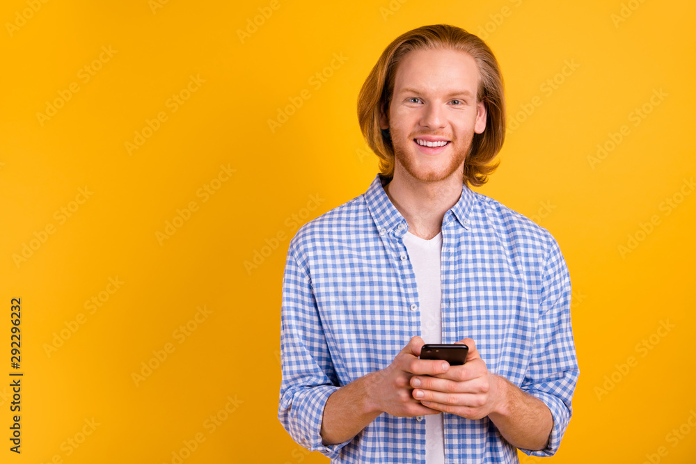 Photo of kind friendly cheerful blogging networker browsing through his phone standing smiling toothily wearing blue shirt isolated with vibrant color background Photo of kind friendly cheerful blogging networker browsing through his phone standing smiling toothily wearing blue shirt isolated with vibrant color background