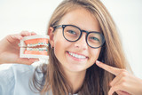 Model of a dental braces in the hand of a young girl with aligned teeth after the process of using a dental brace