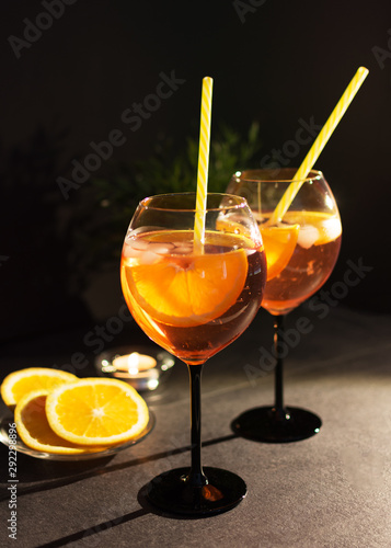 Two glasses of aperol spritz cocktail with orange slices on black background.