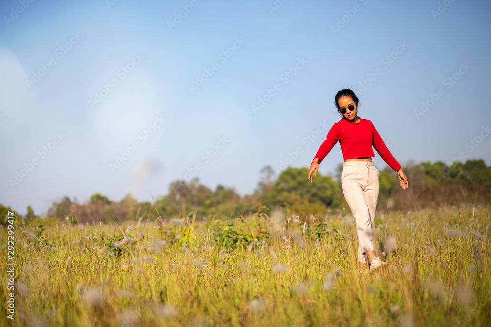 Hipster Asian woman in red and sunglasses on white flower and grass field Hipster Asian woman in red and sunglasses on white flower and grass field