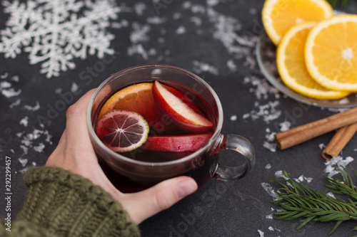 Woman holding a glass cup of hot Christmas mulled wine in hands, closeup. Winter christmas beverage.