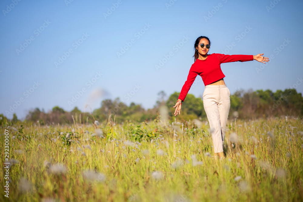Hipster Asian woman in red and sunglasses on white flower and grass field Hipster Asian woman in red and sunglasses on white flower and grass field
