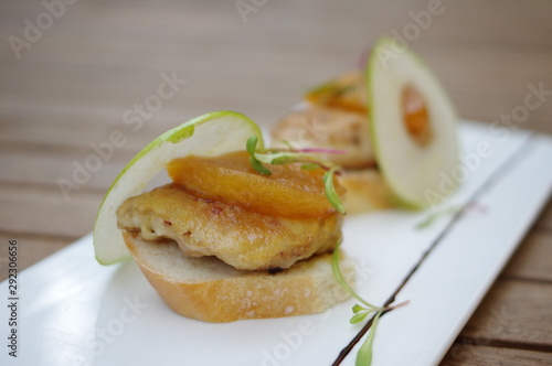 Chicken tapas with peach and apple slice on white rectangle plate in Spanish cuisine restaurant