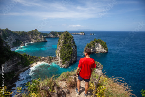 Happy man standing and looking on the rock. Thousand Island Viewpoint Nusa Penida, Indonesia. photo