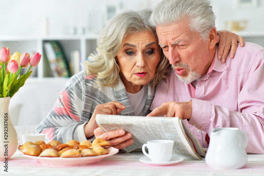 Close up portrait of happy senior couple reading newspaper