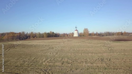 Slow and steady drone shot closing in to windmill on a sunny autumn day. Drone flying over the harvested grain field photo