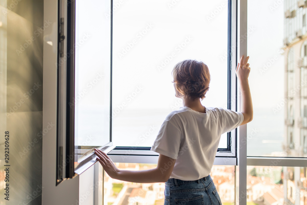 Young woman open window in the morning at home Young woman open window in the morning at home