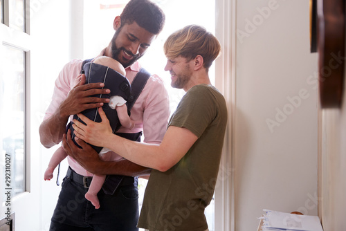 Same Sex Male Couple With Baby Daughter In Sling Opening Front Door Of Home photo