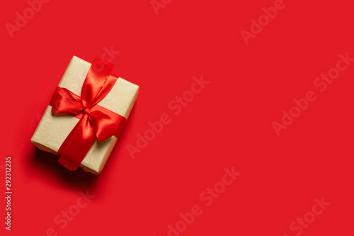 Christmas present. Creative banner with craft box and red ribbon on a red background.