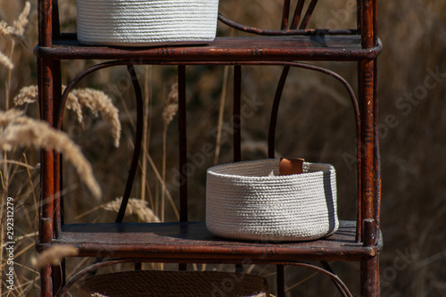 White baskets on old brown whatnot on dry grass field background photo