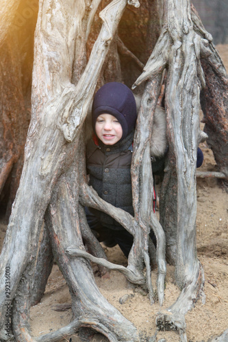 happy smiling boy in warm clothes and hat covering his neck from cold wind llooking at camera in autumn outdoor photo