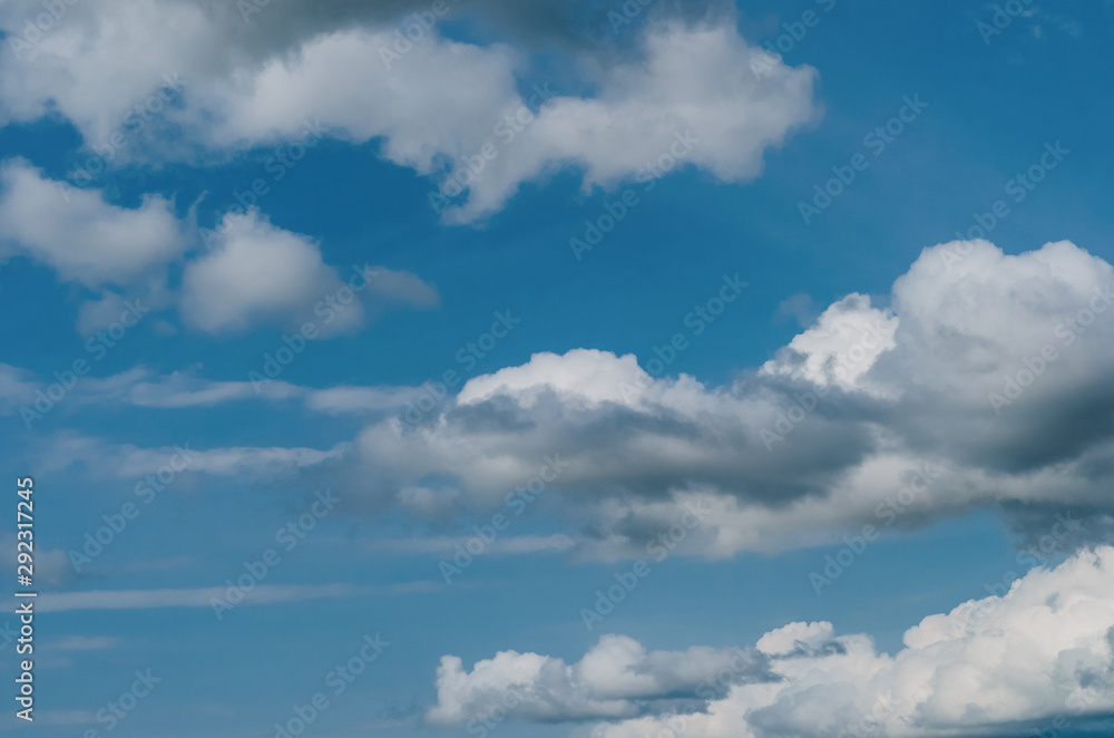 fluffy white-gray clouds slowly floating across the blue sky