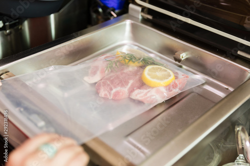 Close-up of woman using vacuum seal machine for meal packing.