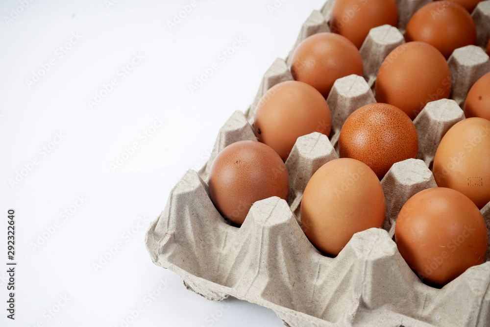 Raw brown chicken eggs in a paper grey crate carton isolated on white background.