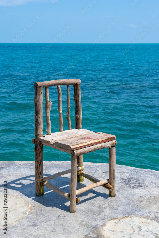 Wooden chair in empty cafe next to sea water in tropical beach . Island Koh Phangan, Thailand Wooden chair in empty cafe next to sea water in tropical beach . Island Koh Phangan, Thailand