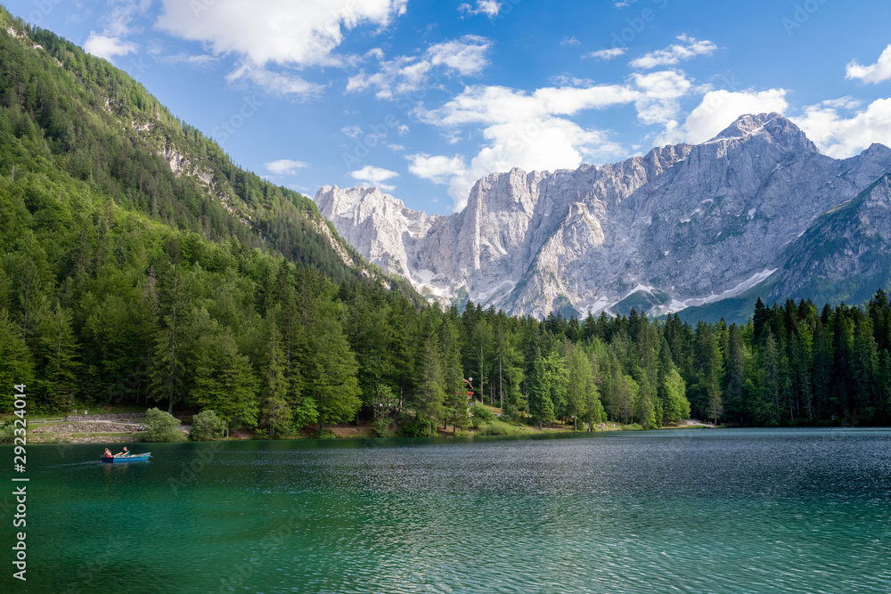 People boating and enjoy beautiful land scape of Lago di Fusine, the lake with background of Julian alps in Italy.