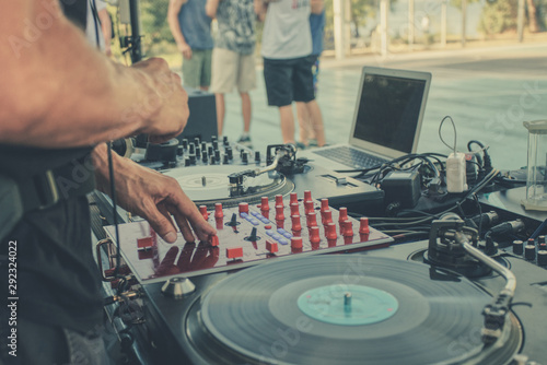 Outdoor music party. Dj playing on vinyl. Dj s hands and turntable close up  blurred people on the background
