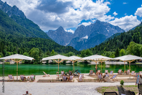 Tourist sit on the chairs with umbrella looking at beautiful landscape of Jasna lake, the small turquoise lake with background of mountain. photo
