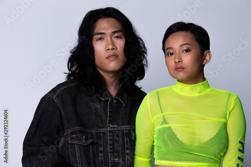 Two Fashion Young Unisex Asian Woman and man beautiful make up fashion wear Jean jacket and green neon shirt, high platform shoes and nose ring. Studio Lighting gray Background isolated copy space photo