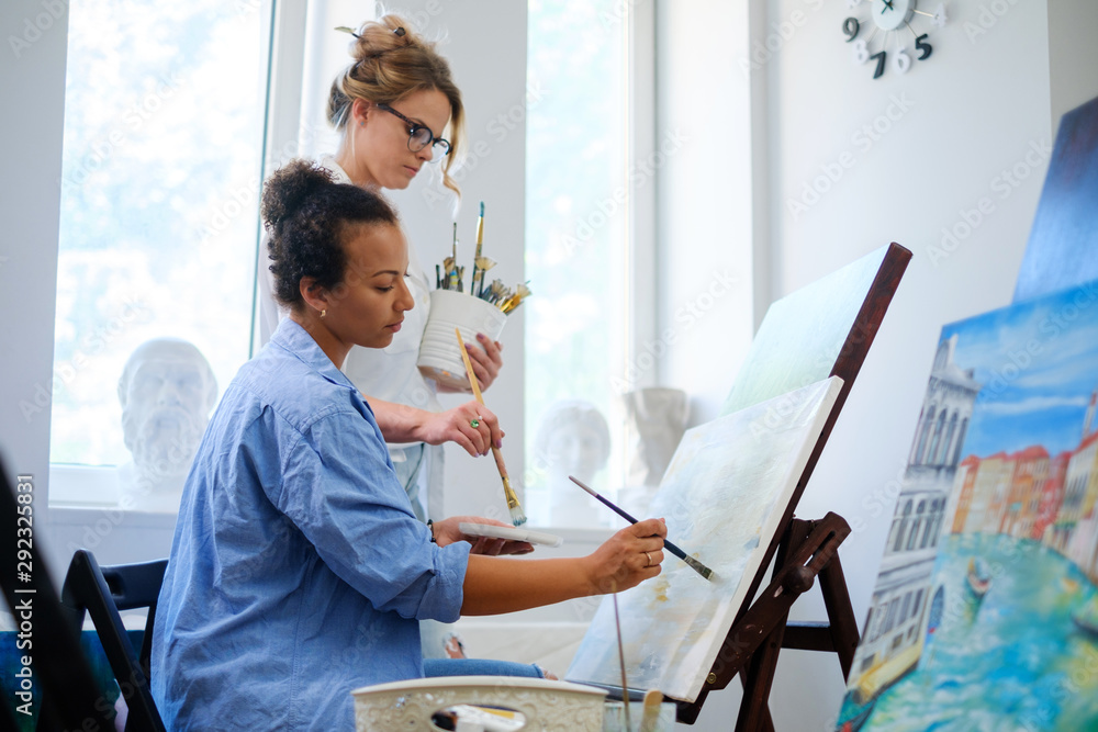 Obraz premium Creative painter and her protege working in a studio