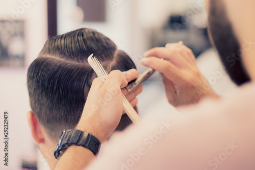 Barber using scissors and comb. Man getting haircut in barber shop. Modern hair salon concept.
