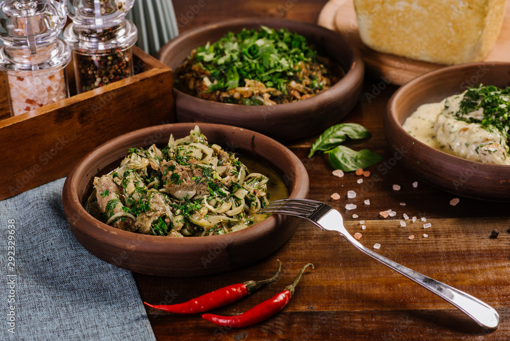 Fototapeta premium Dish with chopped meat with sauce and herbs on the wooden background