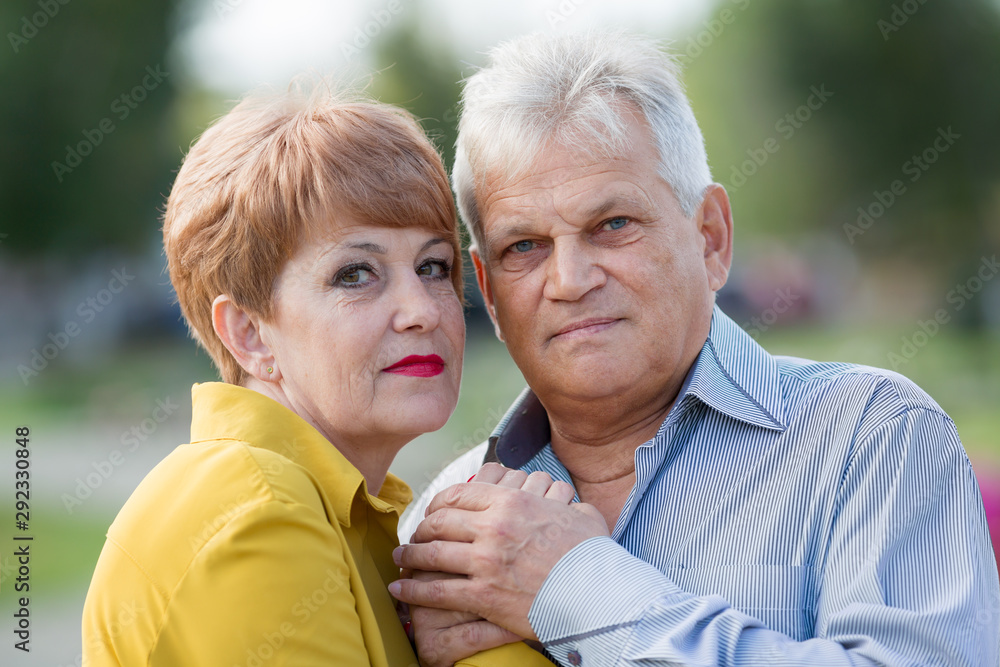 Beautiful married couple of seniors. Senior citizen blue shirt and an elderly wife in a yellow dress outdoors.