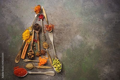 Fototapeta Naklejka Na Ścianę i Meble -  A variety of spices in spoons in the shape of a Christmas tree on a dark rustic background. Abstract christmas tree. Top view, flat lay, copy space.