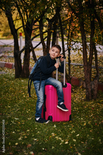 A boy with a suitcase is on the road on a journey, preparing for the trip