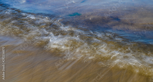 Waves on the seashore captured with a slow shutter speed. Natural abstract motion background.