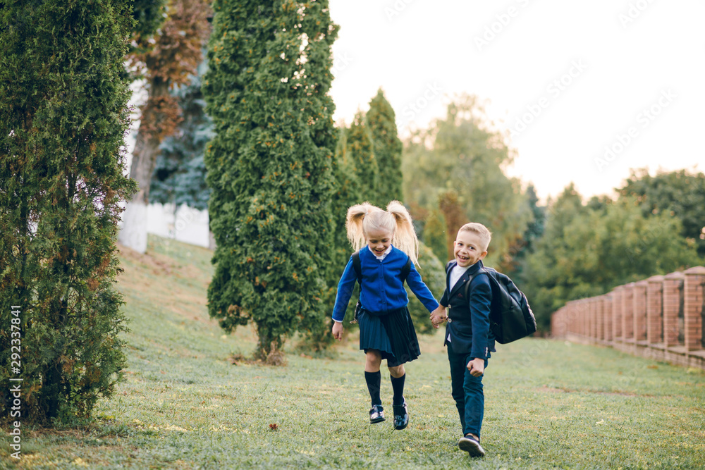 Obraz premium Cute kids with backpacks on their back running to school having fun. Back to school.