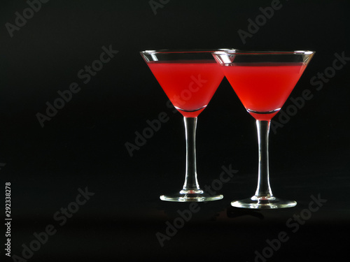 Classic Bacardi alcoholic cocktail of bright red color from white rum, lime juice and grenadine, in two conical cocktail glass on a dark background