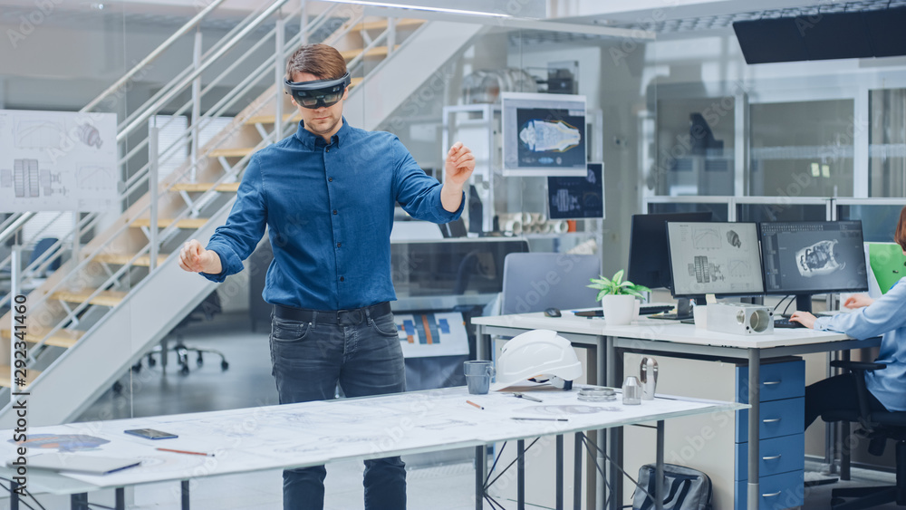 Engineering Software Developer Wearing Virtual Reality Headset Uses Gestures to Interact with Augmented Reality while Designing Industrial Engine Model in Modern Facility. AR Mock-up Concept