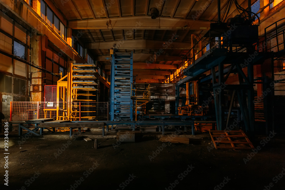 Abandoned brick and paving slabs factory at night. Old rusty machinery