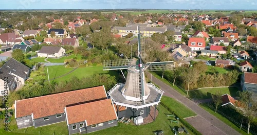 A Traditional Windmill “De Verwachting” in Hollum, the Dutch Island Ameland, The Netherlands. Flying Backwards. 4K Drone Footage. photo