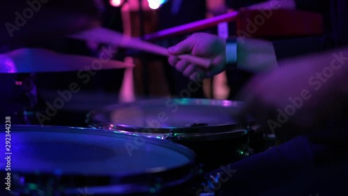 Drummer perform modern music at a party. Man in black perform jazz and soul songs at nightclub. Musician play drum kit with drumsticks in a crowd under muffled lighting, close-up. Relaxing atmosphere.