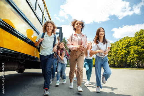 Classmates running from school bus back home looking forward smiling happy photo