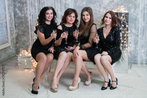 The company of very nice young women with glasses of champagne wine celebrates Christmas, the new year.