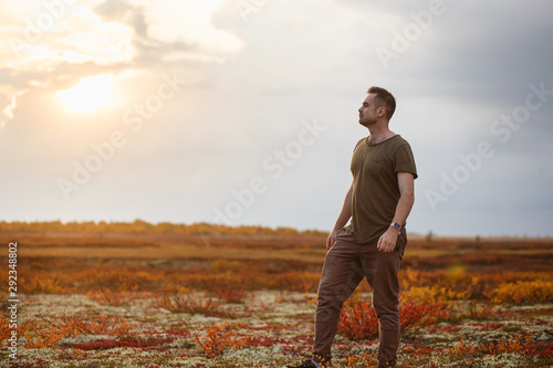 Gordeous man resting in autumn tundra on sunset. Unity with nature concept.. photo