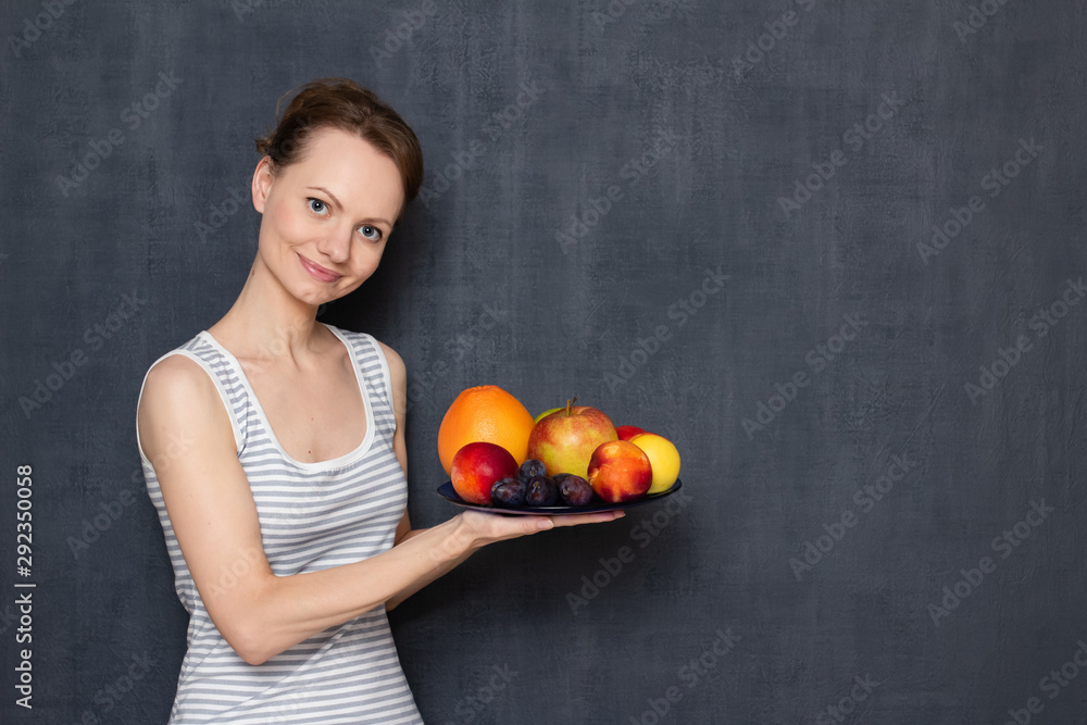 Portrait of happy cheerful girl holding plate with ripe fruits Portrait of happy cheerful girl holding plate with ripe fruits