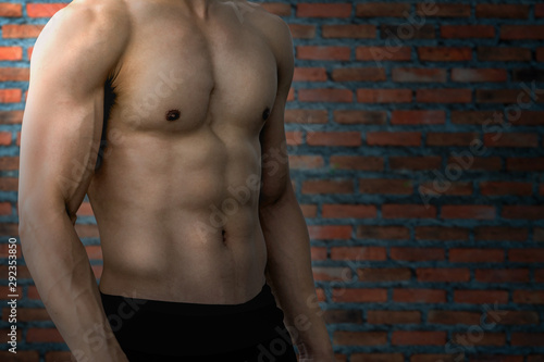 Muscular bodybuilder guy doing posing over brick wall background