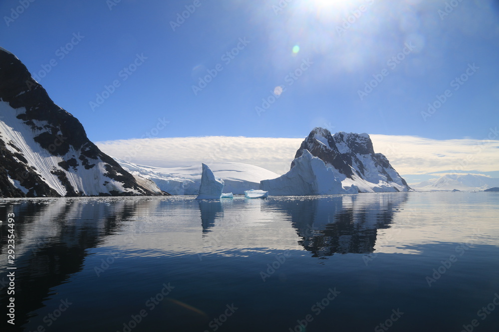 spokojne zimne wody pomiędzy ośnieżonych skałami u wybrzeży antarktydy w piękny słoneczny dzień - obrazy, fototapety, plakaty 