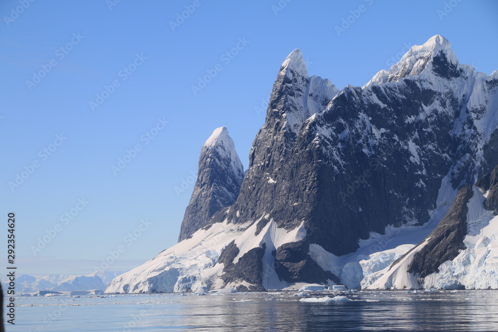 spokojne zimne wody pomiędzy ośnieżonymi skałami u wybrzeży antarktydy w piękny słoneczny dzień
