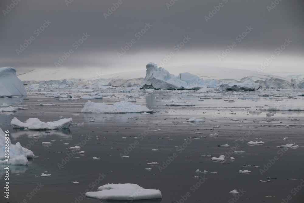 malownicze kry i góry lodowe na spokojnym morzu w pochmurny dzień - obrazy, fototapety, plakaty 