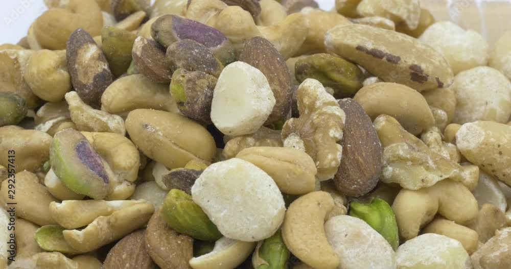 Natural various dry toasted of mixed nuts with almonds, cashews, macadamias, pistachios, walnuts for healthy eating snack food, diet concept, rotation background.