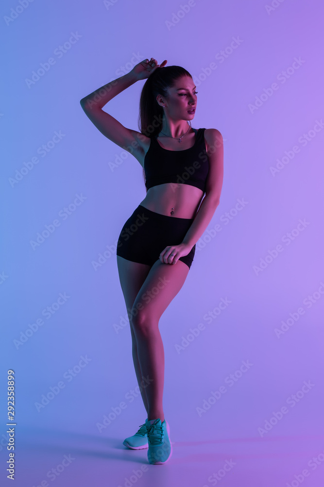 Full length portrait of attractive woman wearing black tracksuit isolated over purple background Full length portrait of attractive woman wearing black tracksuit isolated over purple background